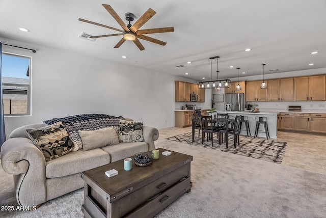 living area with recessed lighting, visible vents, and light carpet