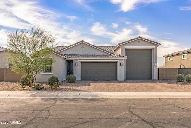 view of front facade featuring an attached garage, fence, driveway, and stucco siding