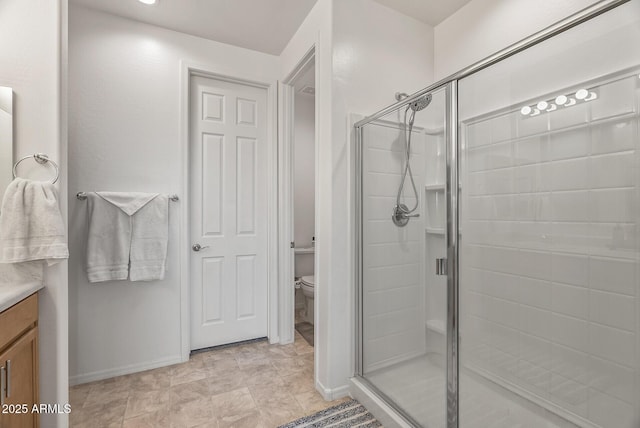 full bath with baseboards, a shower stall, vanity, and toilet