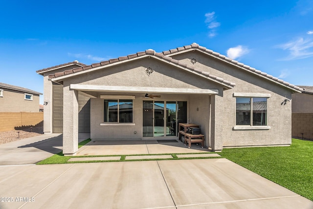 back of house with stucco siding, a lawn, a ceiling fan, fence, and a patio area