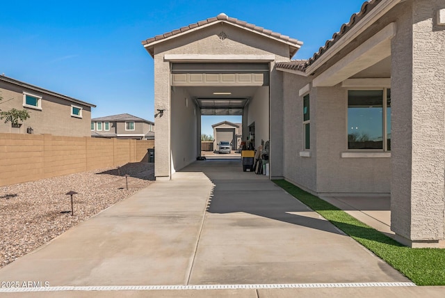 exterior space with stucco siding, a tile roof, and fence