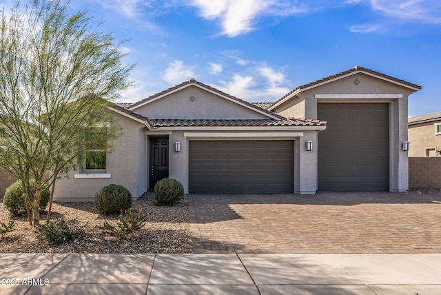 ranch-style house with stucco siding, a tiled roof, decorative driveway, and a garage