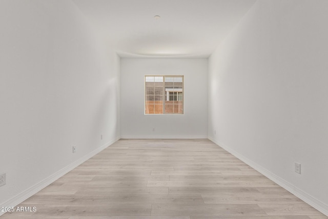 spare room featuring baseboards and light wood finished floors