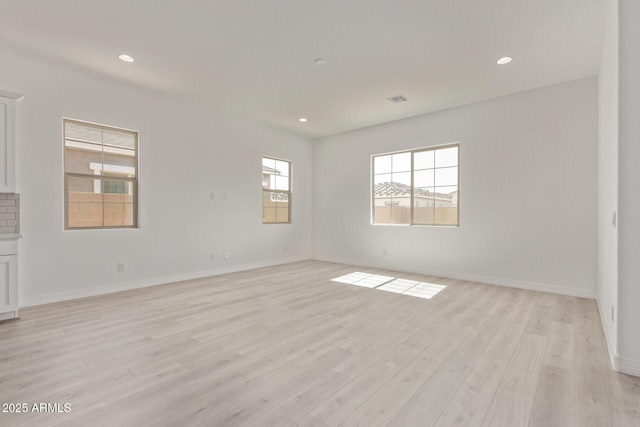 empty room with baseboards, visible vents, light wood-style flooring, and recessed lighting
