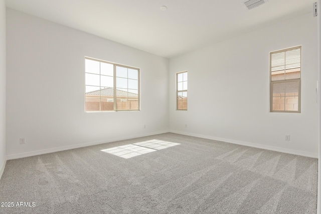 carpeted empty room featuring baseboards and visible vents