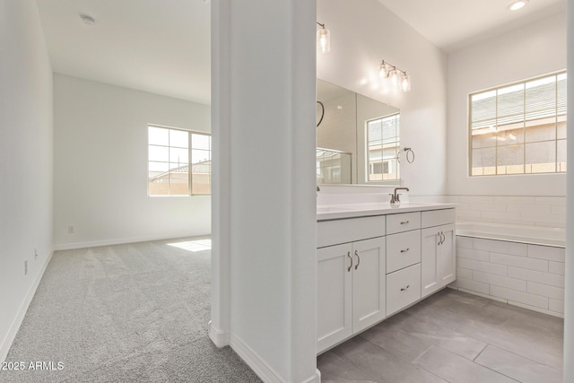 bathroom featuring baseboards, vanity, and a relaxing tiled tub