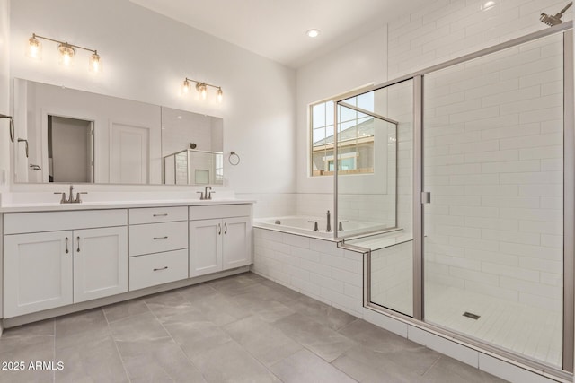 bathroom with double vanity, a sink, a stall shower, and a garden tub