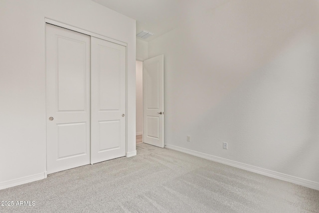 unfurnished bedroom with light colored carpet, visible vents, a closet, and baseboards