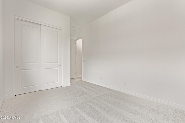 unfurnished bedroom with carpet flooring, baseboards, and a closet