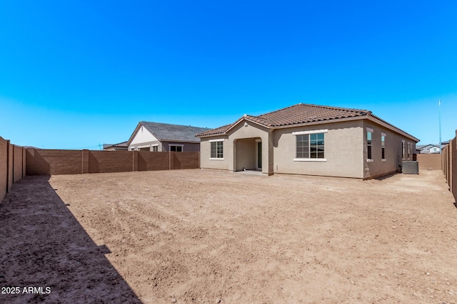 back of property with cooling unit, a fenced backyard, a tile roof, and stucco siding