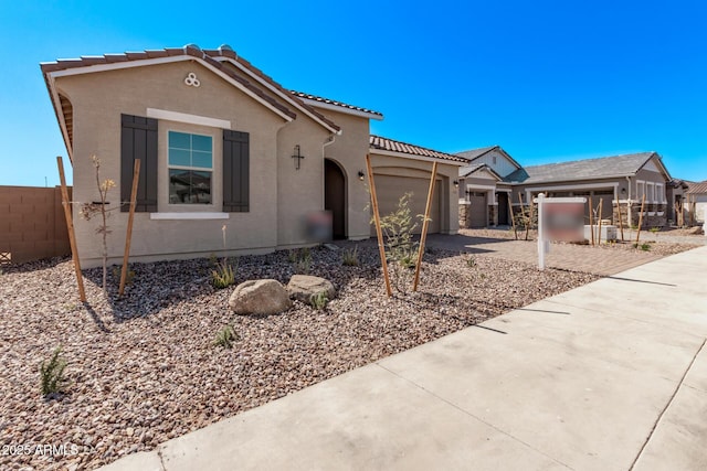 view of front of home with a tile roof, concrete driveway, stucco siding, fence, and an attached garage