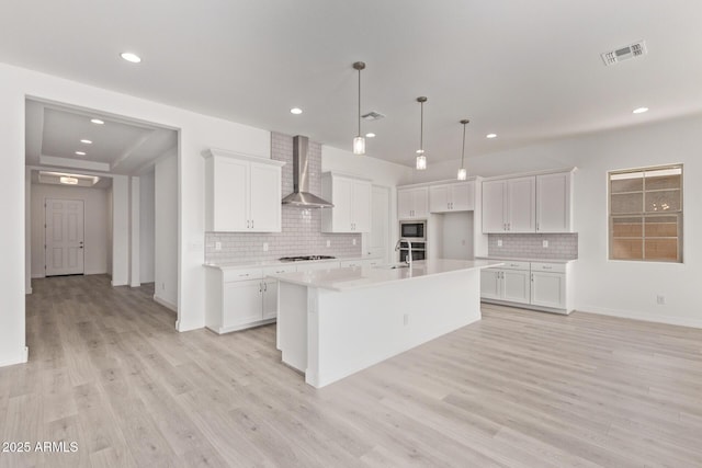kitchen featuring a sink, white cabinetry, wall chimney exhaust hood, gas stovetop, and visible vents