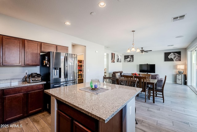 kitchen with light hardwood / wood-style floors, light stone countertops, and stainless steel fridge with ice dispenser