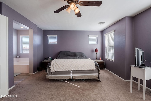 bedroom featuring ceiling fan, light colored carpet, and ensuite bath