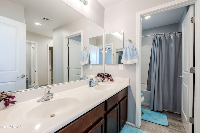 full bathroom with hardwood / wood-style flooring, toilet, vanity, and shower / tub combo