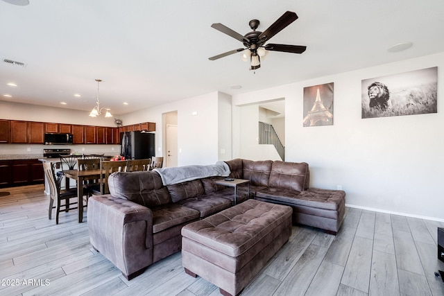 living room with ceiling fan with notable chandelier and light wood-type flooring