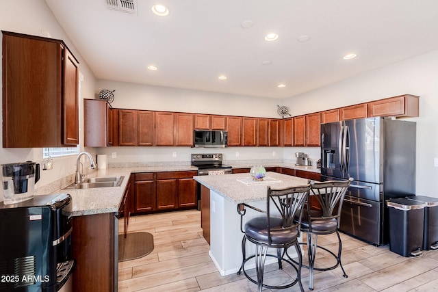 kitchen with light stone counters, stainless steel appliances, a breakfast bar area, and a kitchen island