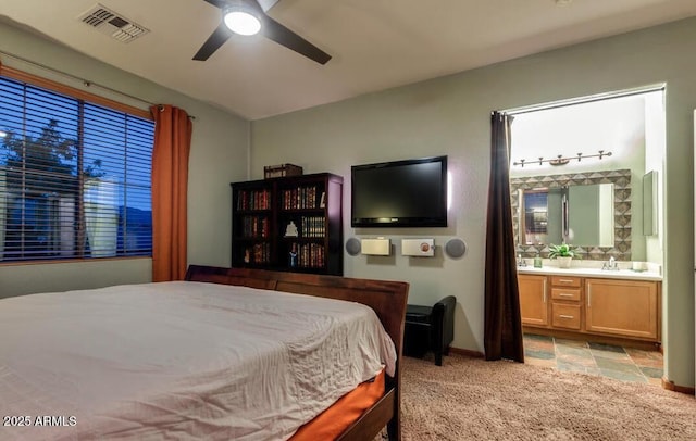 bedroom with ensuite bathroom, sink, light colored carpet, and ceiling fan