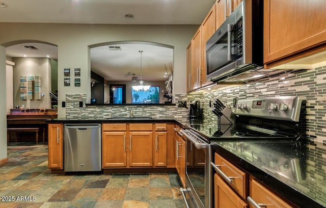 kitchen featuring sink, hanging light fixtures, appliances with stainless steel finishes, a notable chandelier, and decorative backsplash