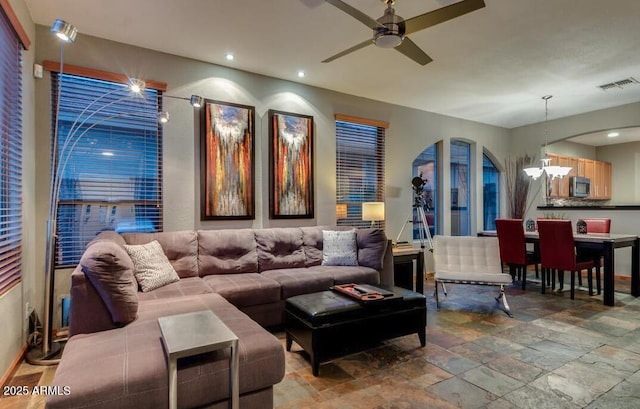 living room featuring ceiling fan with notable chandelier