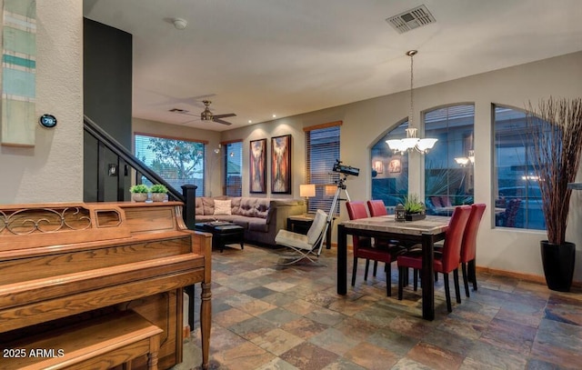 dining space featuring ceiling fan with notable chandelier