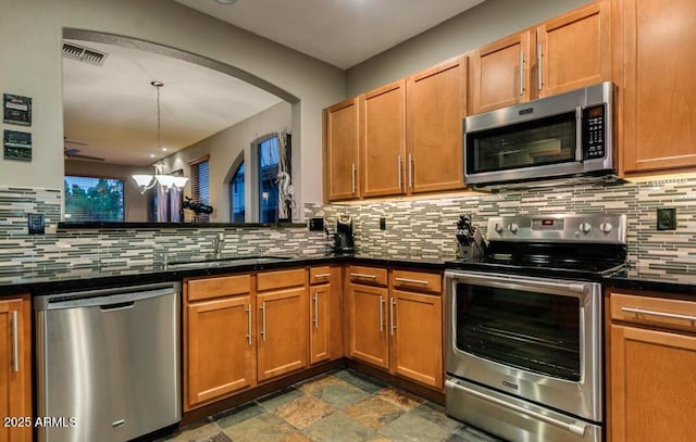 kitchen featuring sink, hanging light fixtures, a notable chandelier, stainless steel appliances, and decorative backsplash