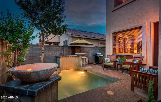 patio terrace at dusk featuring a grill and exterior bar