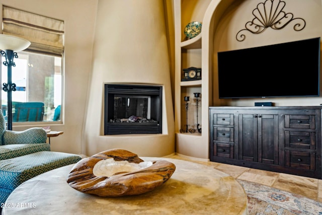 living room with built in shelves and a glass covered fireplace