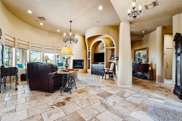 living room featuring a chandelier, built in features, recessed lighting, stone tile flooring, and a towering ceiling