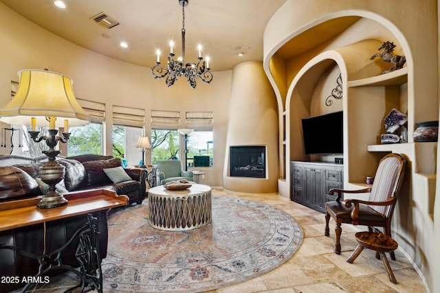 living room featuring a fireplace, a chandelier, recessed lighting, stone finish floors, and a high ceiling