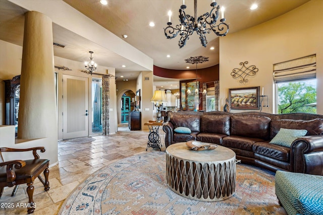 living area featuring a chandelier, stone tile flooring, arched walkways, recessed lighting, and baseboards