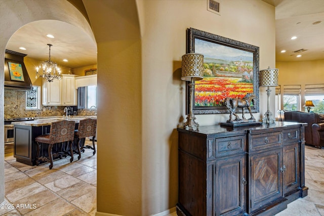 kitchen featuring stainless steel electric stove, arched walkways, recessed lighting, stone tile flooring, and premium range hood