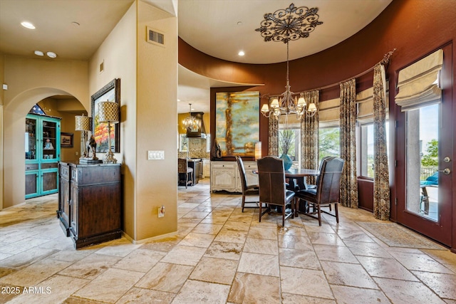 dining space featuring stone tile floors, healthy amount of natural light, a chandelier, recessed lighting, and a high ceiling