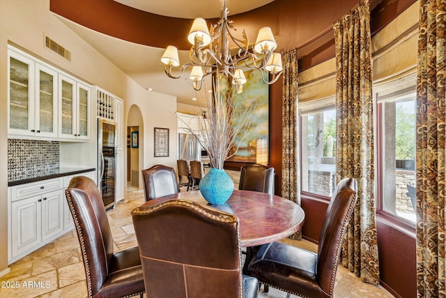 dining space with a chandelier, arched walkways, stone tile floors, and plenty of natural light