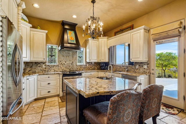 kitchen featuring stainless steel appliances, premium range hood, recessed lighting, a sink, and stone tile flooring