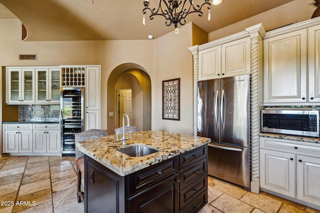 kitchen with stainless steel appliances, a sink, wine cooler, and stone tile floors