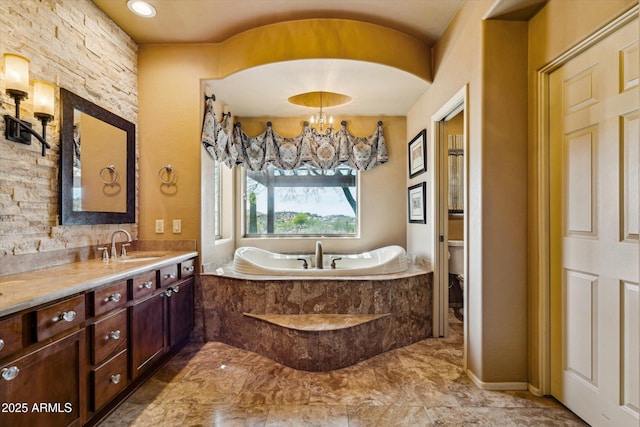 full bath with toilet, vanity, a bath, a chandelier, and marble finish floors