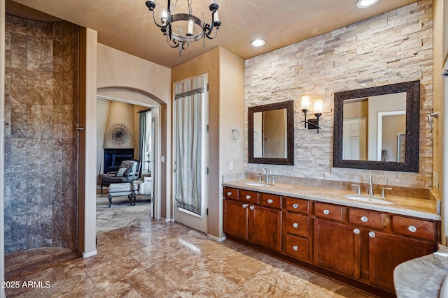 full bath with a chandelier, double vanity, a fireplace, recessed lighting, and baseboards