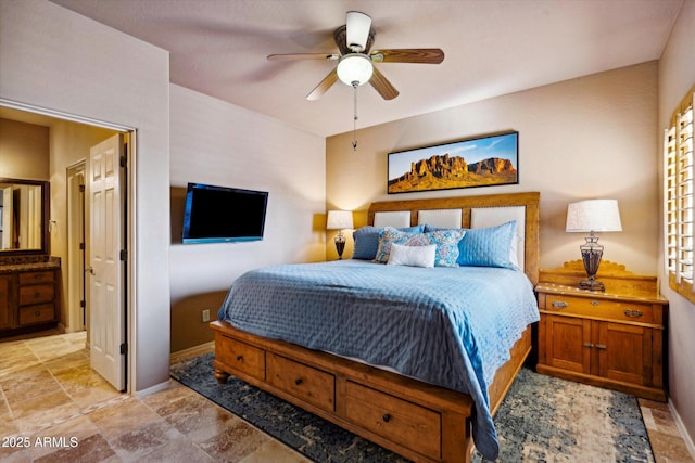 bedroom with baseboards, ensuite bathroom, light stone finish floors, and a ceiling fan