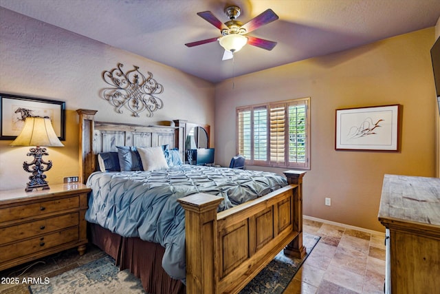 bedroom featuring stone tile flooring, baseboards, and ceiling fan
