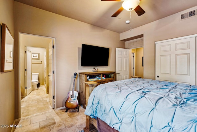 bedroom with baseboards, ensuite bath, light stone finish flooring, and ceiling fan
