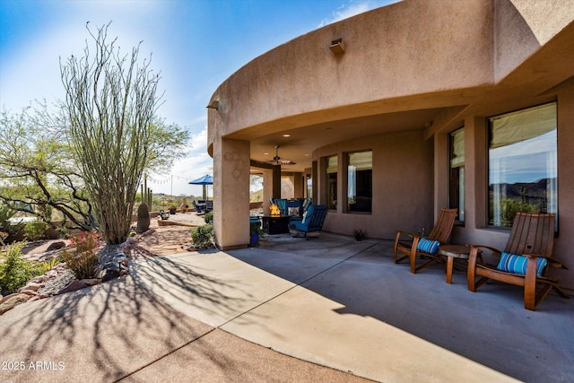 view of patio / terrace featuring a ceiling fan and a fire pit