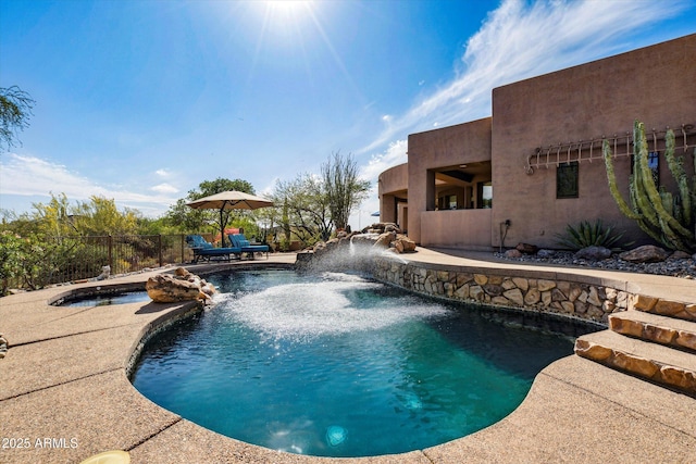 view of swimming pool with fence, a patio, and a pool with connected hot tub