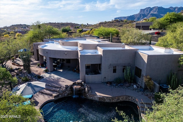rear view of property with stucco siding, a patio area, a mountain view, and an outdoor pool