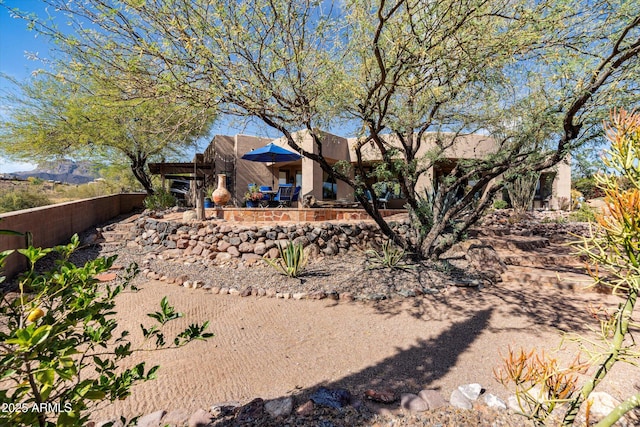 rear view of house with stucco siding and fence
