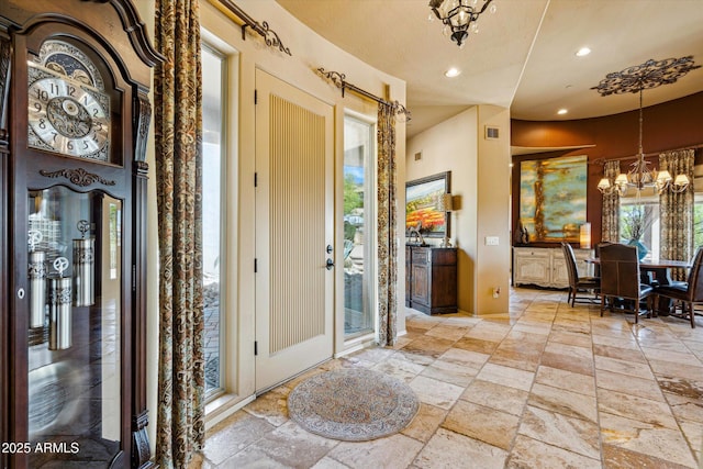 foyer entrance featuring stone tile flooring, a chandelier, and recessed lighting