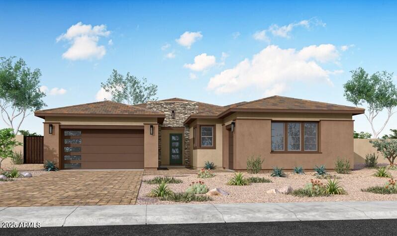 prairie-style house with decorative driveway, a garage, fence, and stucco siding