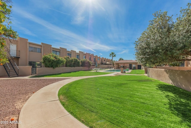 view of home's community with a swimming pool, a residential view, fence, and a lawn