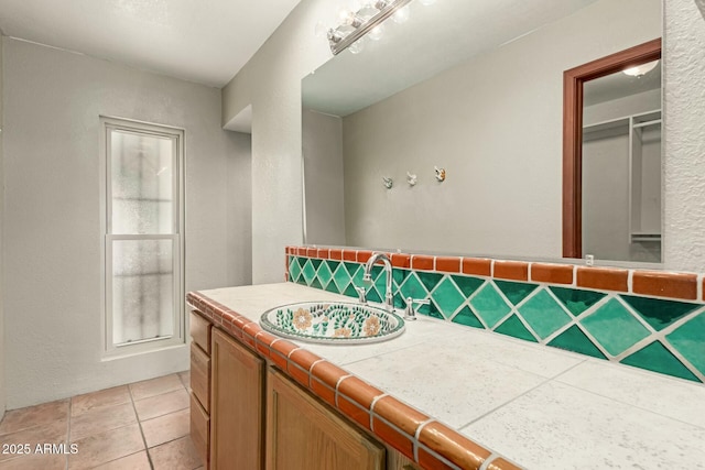 bathroom with tasteful backsplash, a textured wall, vanity, and tile patterned floors