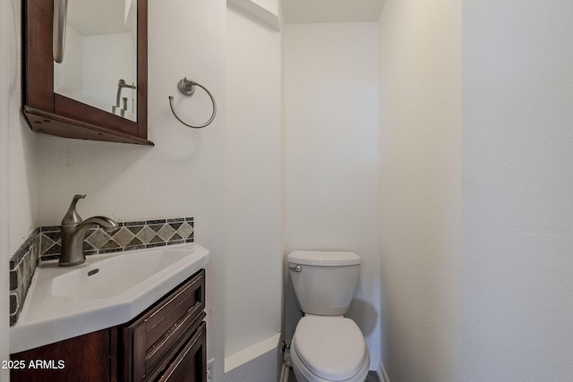 bathroom with vanity, toilet, and backsplash